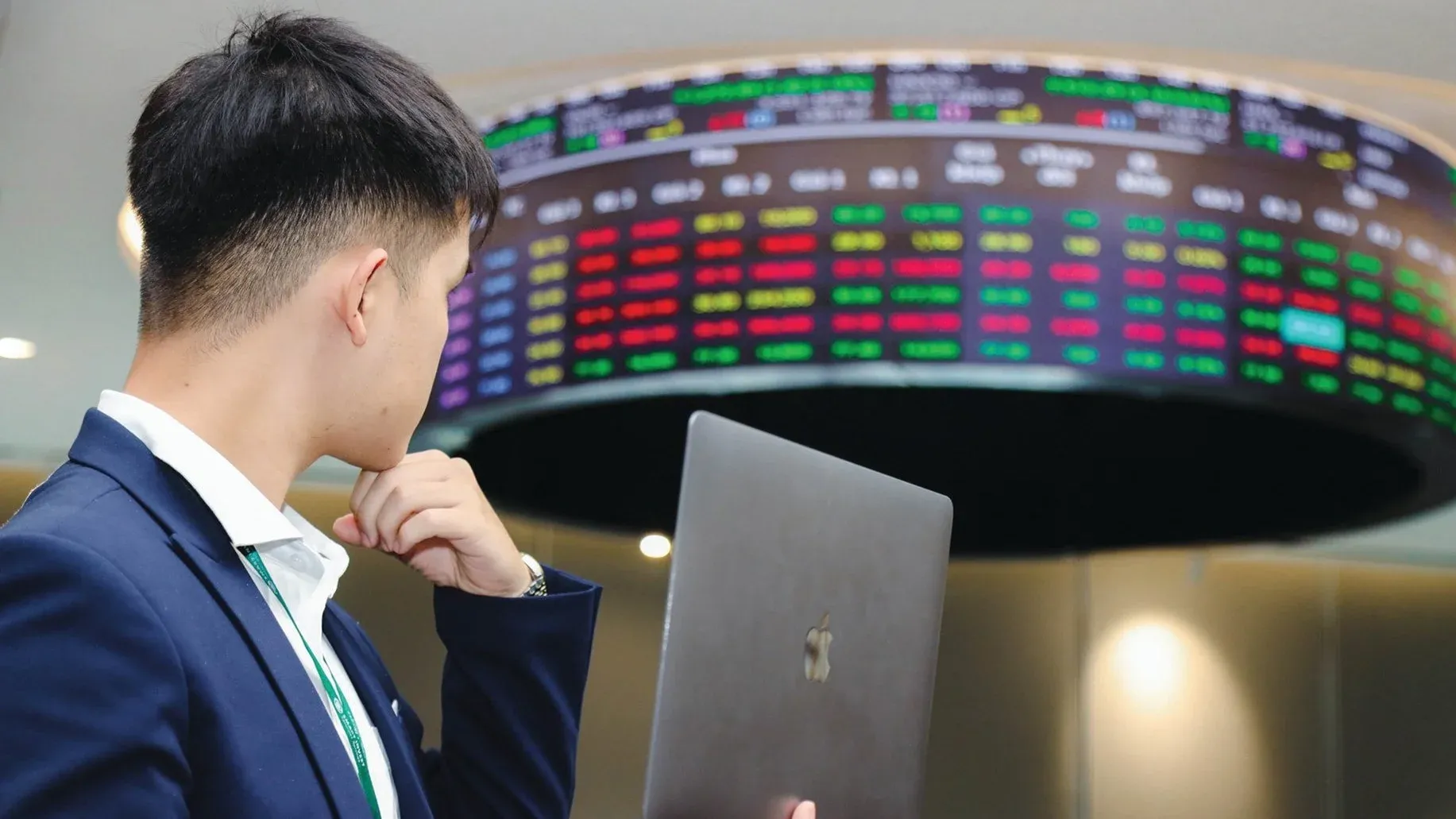 Investor contemplating decisions in front of trading board